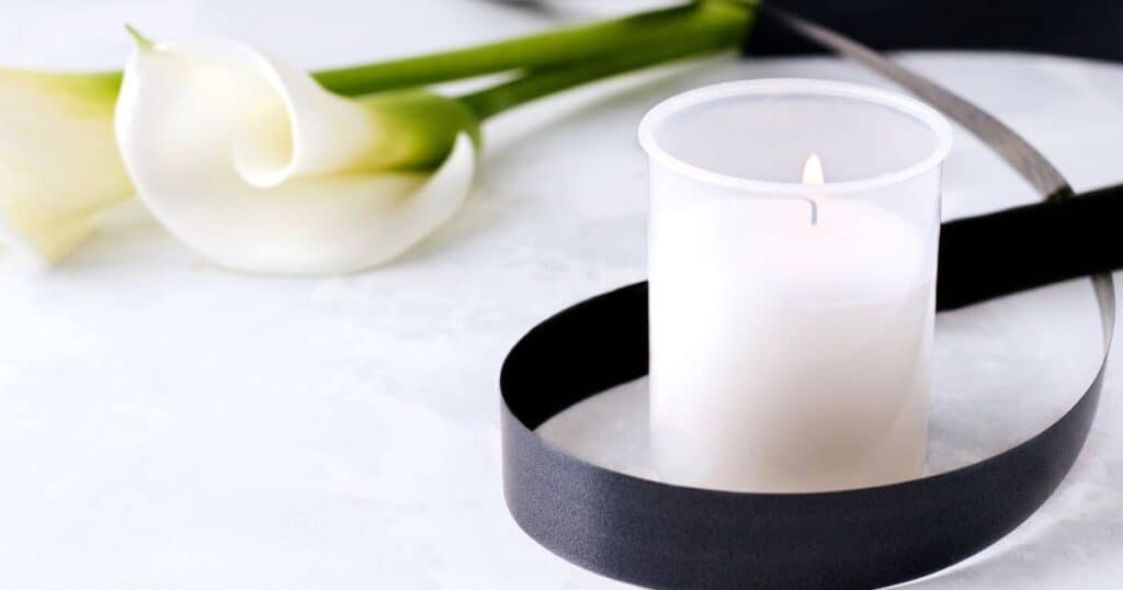 White candle in glass votive with white lily flower