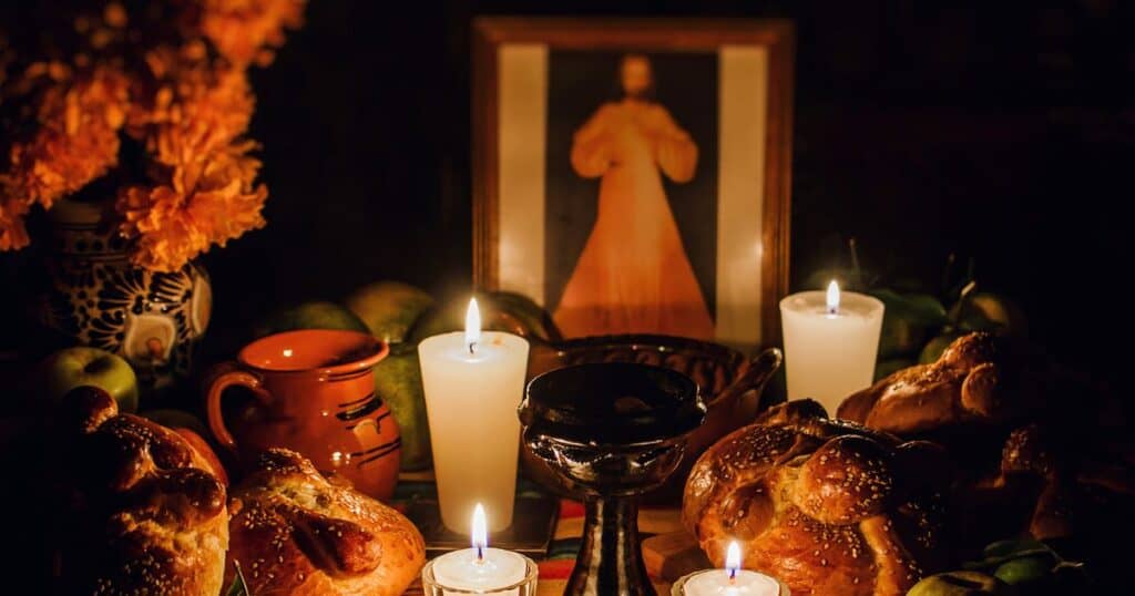 Traditional Día de los Muertos altar lit by candles with bread, marigolds, and a framed photo — symbolizing remembrance and love.